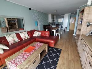 a living room with a red couch and a table at Lagoon Beach Apartment 309 in Cape Town