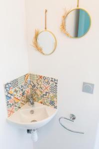 a bathroom with a sink and mirrors on the wall at Vacances pour 8 aux portes du Guilvinec in Plomeur