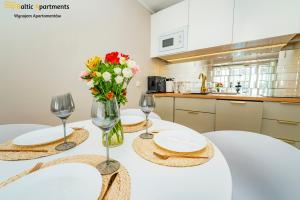 a table with two glasses and a vase of flowers at Baltic Apartments - Sun Towers in Świnoujście