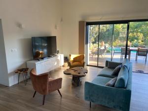 a living room with a blue couch and a tv at VILLA ISULA by Intendance Excellency in Sainte-Lucie de Porto-Vecchio
