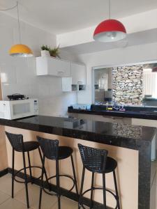 eine Küche mit drei Barhockern und einer Theke in der Unterkunft Casa no Mirante de Escarpas in Capitólio