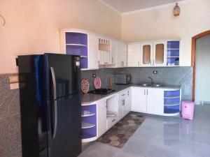 a kitchen with white cabinets and a black refrigerator at Villa Victoria Old Nile View in Luxor
