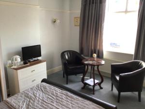 ein Hotelzimmer mit einem Bett, einem Tisch und Stühlen in der Unterkunft Southbourne Guest House in Llandudno