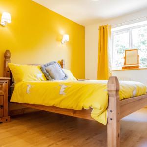 a bedroom with yellow walls and a bed with yellow sheets at Muntjac View, Beechcroft Barns, Cawston, Norfolk in Norwich