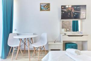 um quarto com 2 cadeiras brancas, uma mesa e uma televisão em Studio Mar Sea Tomis Villa Mamaia Nord - Năvodari em Mamaia Nord – Năvodari