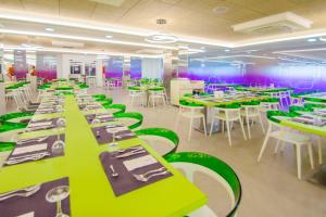 une salle à manger avec des tables vertes et des chaises blanches dans l'établissement Hotel Servigroup Romana, à Alcossebre