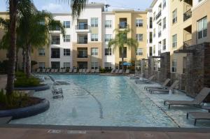 una piscina con sillas, palmeras y edificios en Domain at CityCentre en Houston