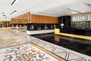 een lobby met een grote kamer met een open haard bij Mövenpick Hotel Karachi in Karachi