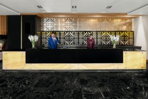 a lobby with a black and yellow wall with three people at Mövenpick Hotel Karachi in Karachi