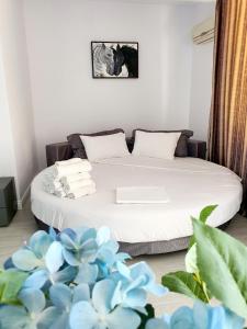 Coral Residence -Mamaia Nord في مامايا: غرفة نوم مع سرير مع الزهور الزرقاء على الأرض