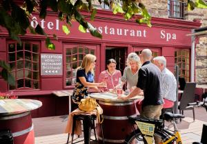 people sitting at a table in front of a restaurant at Logis Hotel, restaurant et spa Le Relais De Broceliande in Paimpont