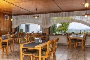 un restaurant avec des tables, des chaises et des fenêtres dans l'établissement Pension Wittgensteiner Schweiz, à Bad Berleburg