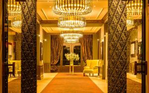 a lobby with a chandelier and a hallway with chairs at Le Palais Art Hotel Prague in Prague