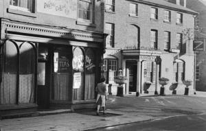 Un uomo in piedi su una strada di fronte a un edificio di Cain Valley Hotel a Llanfyllin