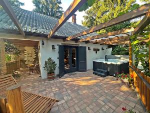 un patio con bañera de hidromasaje y pérgola de madera en Cityside Cottage, en Eger