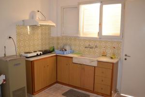 una cucina con armadi in legno, lavandino e finestra di Studio Lantzos a Oreoi