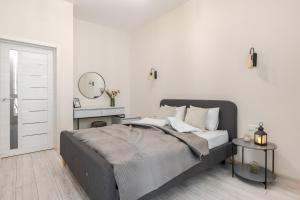ein weißes Schlafzimmer mit einem Bett und einem Spiegel in der Unterkunft InshiApartments on Pid Dubom 2 in Lwiw