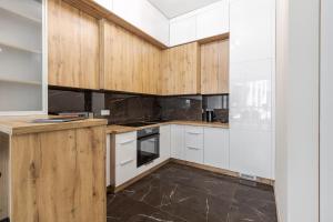 uma cozinha com armários brancos e pisos em azulejo preto em InshiApartments on Pid Dubom 2 em Lviv
