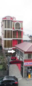 a red building with a car parked in front of it at hotel amber in Batumi