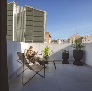 un homme assis sur une chaise sur un balcon dans l'établissement YOURS boutique stay, à Valence