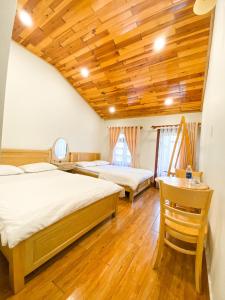 a bedroom with two beds and a wooden ceiling at Jolie Maison Đà Lạt in Da Lat