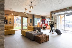 a woman with luggage in a living room with a couch at Résidence Club MMV Samoens in Samoëns