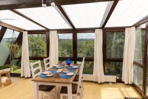 a dining room with a table in a conservatory with windows at Ferienhaus Düperthal in Hilchenbach