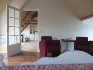 sypialnia z 2 krzesłami, łóżkiem i drzwiami w obiekcie B&B Boerderij Wijtvliet w mieście Langeweg