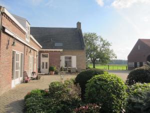 een stenen huis met een patio in een tuin bij B&B Boerderij Wijtvliet in Langeweg