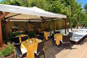 a patio with tables and chairs under a white umbrella at Villa Angelica in Venice-Lido