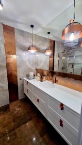 ein Badezimmer mit einem weißen Waschbecken und einem Spiegel in der Unterkunft Lazur Lake in Lyck