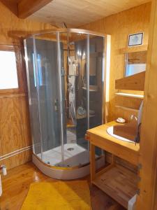 una ducha en una habitación de madera con suelo de madera en Maison de montagne dans charmant village du Capcir, en Fontrabiouse