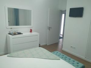 a white bedroom with a white dresser and a mirror at Brava in Vila Franca do Campo