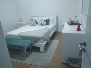 a white bedroom with a bed and a bench at Brava in Vila Franca do Campo