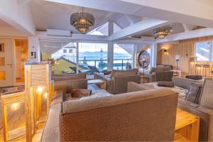 a living room with couches and a table and windows at YachtHotel Helvetia Spa- und Wellnessdomizil in Lindau