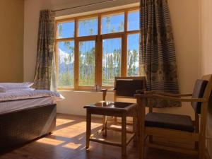 una camera da letto con un letto, una sedia e una finestra di Rabyang Guest House and Homestay a Leh