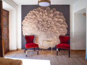 アルカラ・デル・フカルにあるComplejo Casa Carmen Alcalá Del Júcarのリビングルーム(赤い椅子2脚、大きな絵画付)