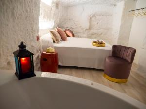 a white bedroom with a bed and a chair at Complejo Casa Carmen Alcalá Del Júcar in Alcalá del Júcar