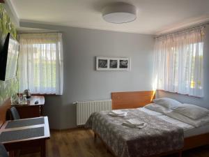 - une chambre avec un lit, un bureau et 2 fenêtres dans l'établissement Pokoje Gościnne Agata, à Grzybowo