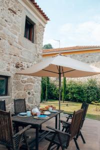 a table with an umbrella in front of a building at Just Like Home - Holly House em Cerveira in Linhares