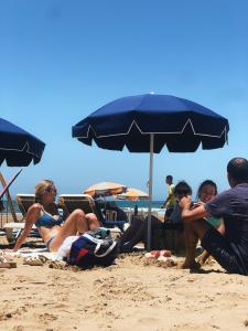 un gruppo di persone sedute in spiaggia sotto un ombrellone di Manzili Surfhouse a Tamraght Ouzdar