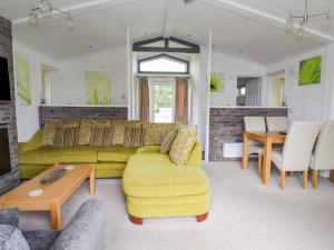 Honeysuckle Lodge في أبرجيل: غرفة معيشة مع أريكة صفراء وطاولة