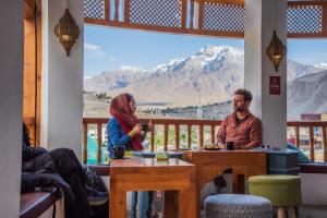 a man and woman sitting at a table in a room with a mountain view at Black Sheep Bed & Breakfast in Kargil +14 photos