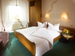 a bedroom with a large white bed with a window at Hotel Lösch Pfälzer Hof in Römerberg