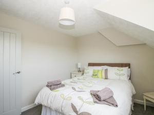 a bedroom with a white bed with towels on it at Rosemary Cottage in Craven Arms