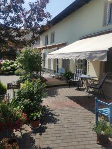 eine Terrasse mit Stühlen, Pflanzen und einem weißen Regenschirm in der Unterkunft Ferienwohnung Uenglingen in Stendal