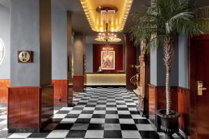 a hallway with a checkered floor and palm trees at Elite Hotel Savoy in Malmö