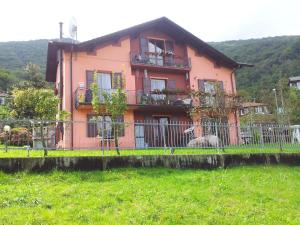 ein rosa Haus mit einem Zaun davor in der Unterkunft I Tre Ciliegi Apartment in SantʼOmobono Imagna