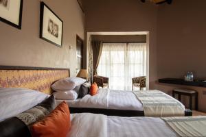 Murchison Falls National ParkにあるSambiya River Lodgeのベッド2台と窓が備わるホテルルームです。