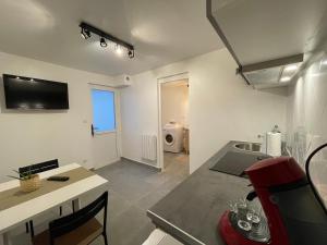 a kitchen with a table and a sink in a room at Grand studio tout équipé proche Paris & Disneyland in Ozoir-la-Ferrière